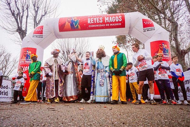 Los Reyes Magos y sus pajes posando ante el arco inflable de la carrera.