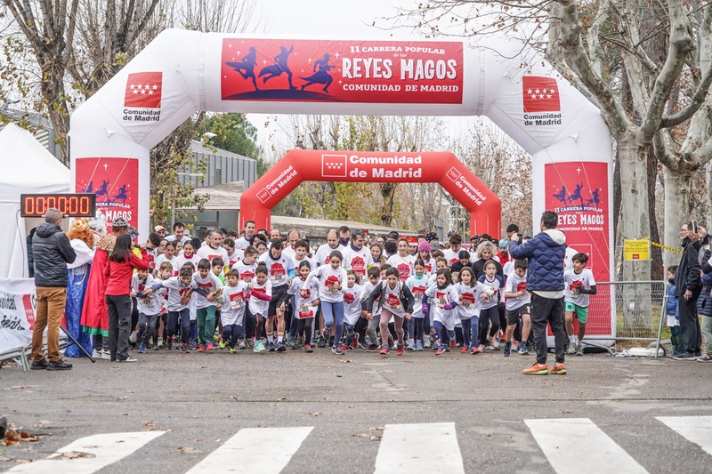 Un grupo numeroso de participantes, muchos de ellos niños, esperando bajo el arco de salida inflable.