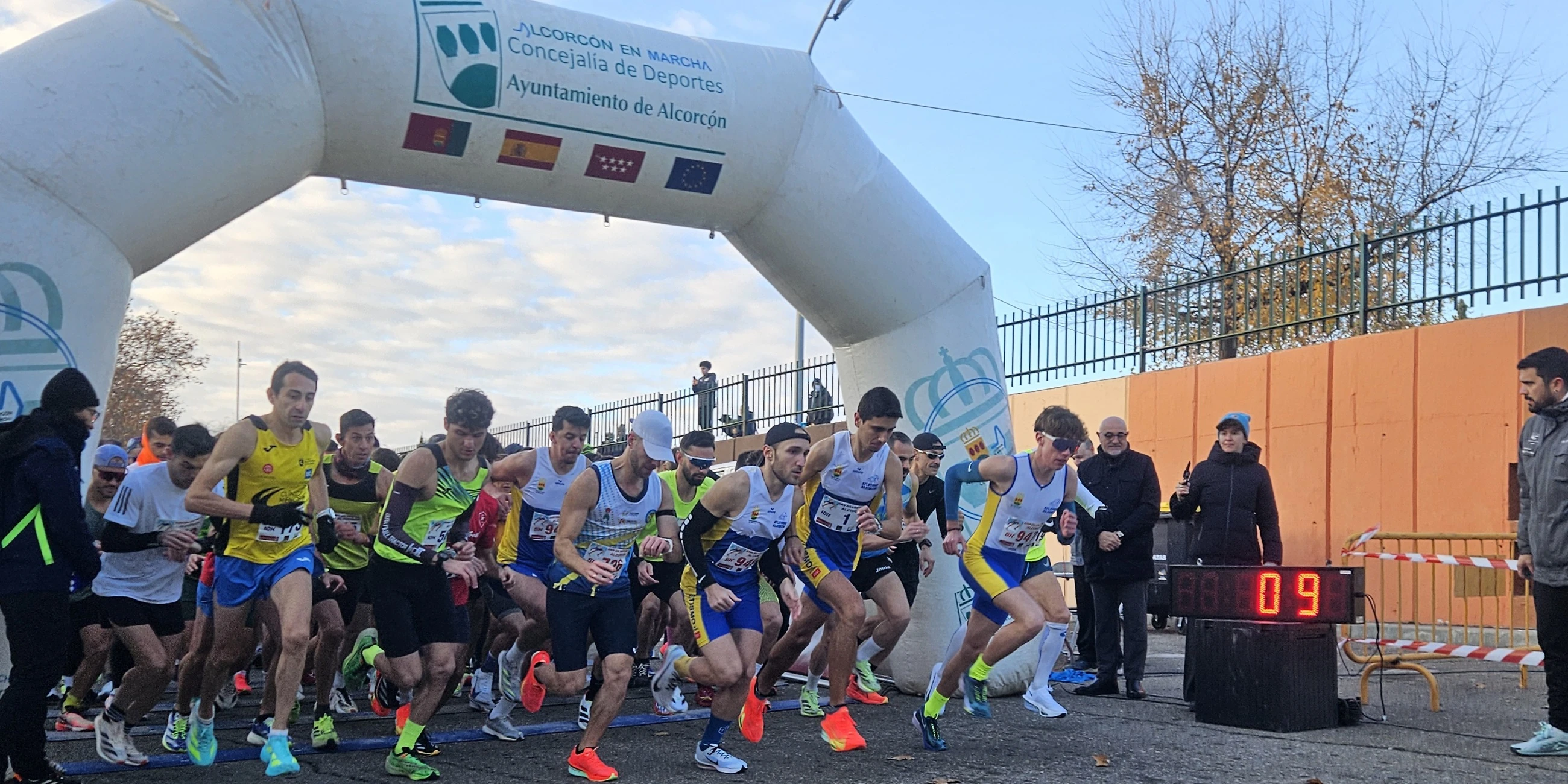 Salida de una carrera: corredores arrancando bajo el arco hinchable de la Concejalía de Deportes del Ayuntamiento de Alcorcón, junto al reloj de carrera