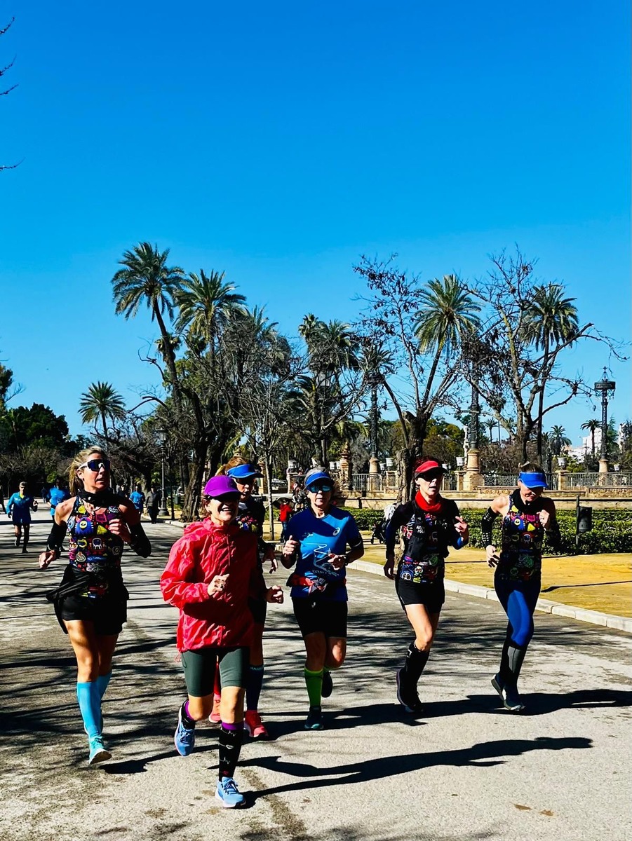 Women runners training as a group along a palm-lined avenue